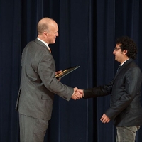 Doctor Potteiger shaking hands with an award recipient in a black jacket